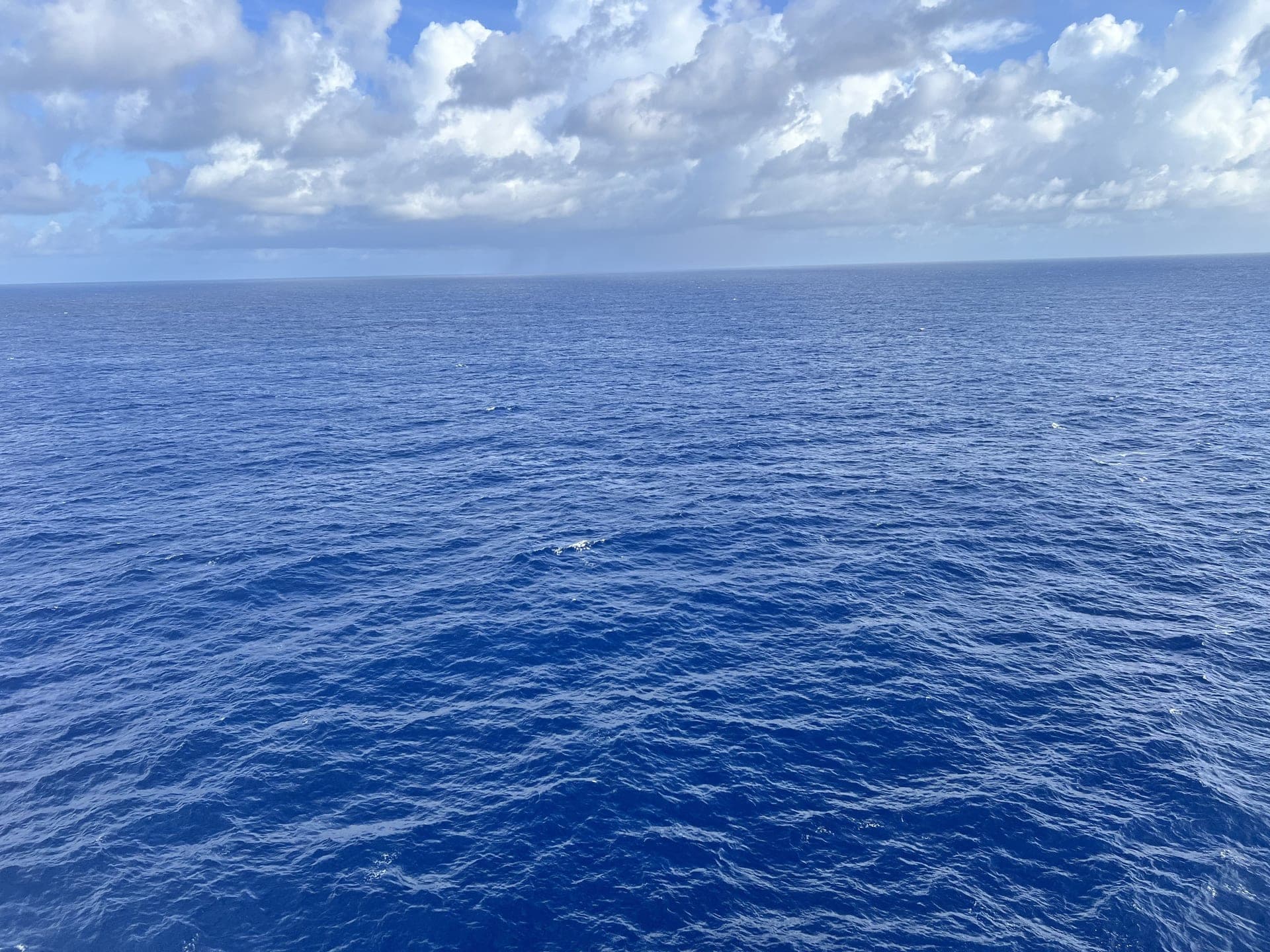Deep blue open ocean under dramatic clouds from a cruise ship